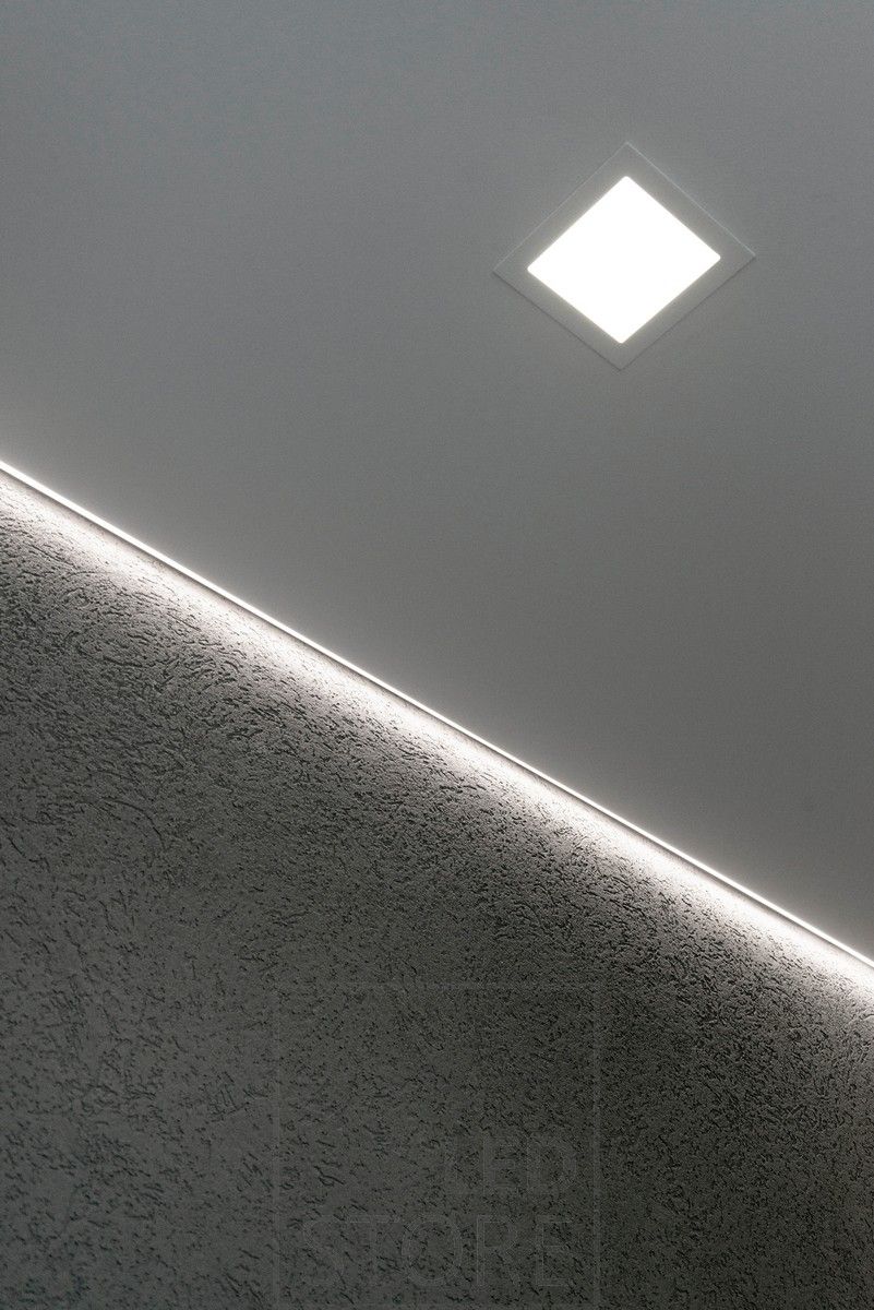 Indirekt belysning som belyser en vägg med struktur. Den indirekta belysningen kompletteras av en brett upplyst panelarmatur som downlight. Ledstore.fi